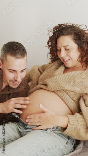Pregnant Latin couple expecting a baby playing with belly