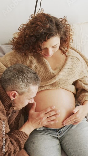 Husband listening to his Latin pregnant wife's baby bump