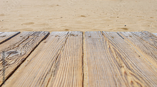A close-up view of weathered wooden planks lying on a golden sandy beach.
