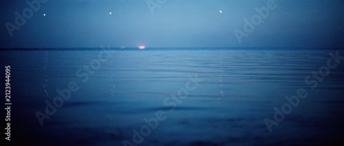 Peaceful twilight over calm water surface with fading sun reflecting on horizon in serene landscape, evoking tranquility and connection to nature