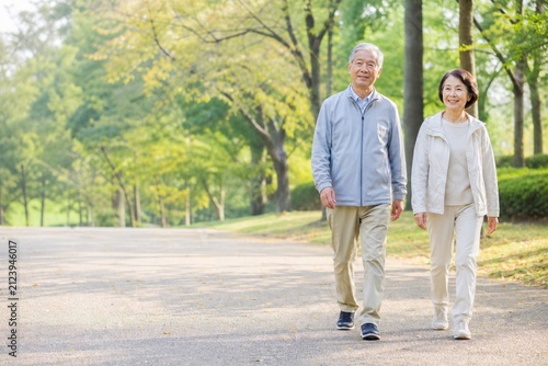 秋の公園を散歩する元気な日本人シニア夫婦