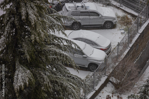 Snow covered the surrounding area and cars in the parking lot. Snowfall and a snow-covered courtyard in cool weather. Winter weather. Snowdrifts covered the cars.