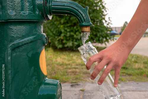 Canvastavla Close-up of a person refilling a reusable glass water bottle from a public drinking fountain outdoors