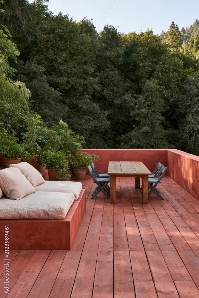 Obraz premium Red outdoor terrace with built in sofa, wooden table and potted plants for patio background and outdoor design
