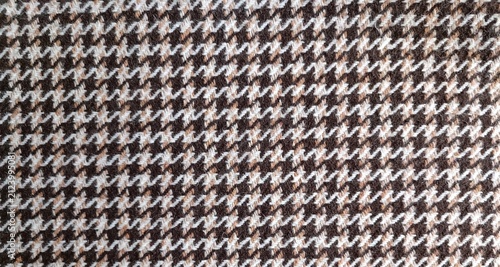 Macro of brown, beige, and white hounds tooth pattern with jagged interlocking four pointed checks. Slightly napped, fuzzy wool texture adds warmth and depth.