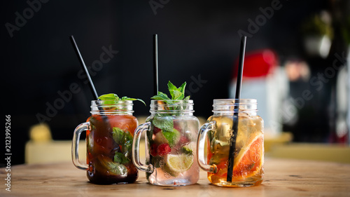 Three jars with various iced tea with fruits and mint.