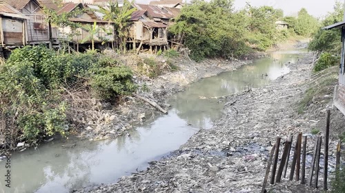 Wide view of contaminated rural river clogged with plastic garbage