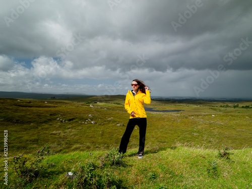 Photography Young woman tourist in a vivid yellow tourist jacket is in a mountains with picturesque background