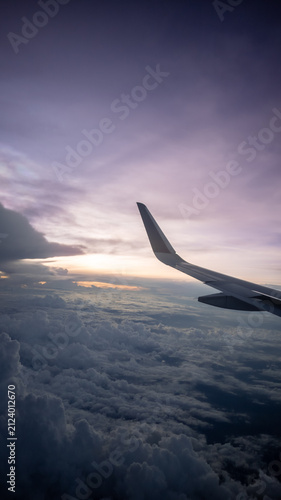 Obraz na płótnie Scenic view of an aircraft wing soaring over a sea of clouds at dusk