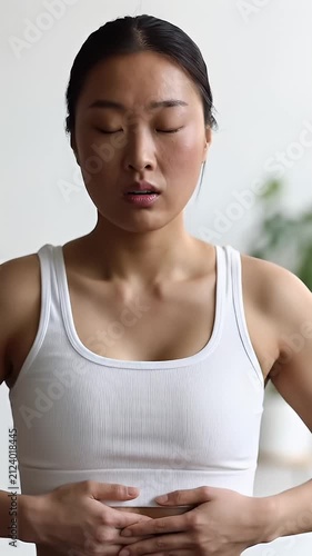 Woman holding her stomach in pain wearing athletic clothing.