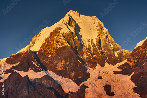 Foto Golden alpenglow ignites the massive east face of Yerupaja, the highest peak in