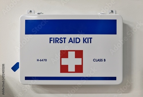 First aid kit medical supplies attached to wall workplace environment.