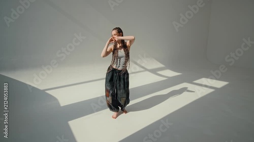Contemporary barefoot dance pose in minimal studio with window light and geometric floor shadow play