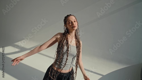 Confident young woman changing fashion poses with raised arms and hands on head in bright sunlit