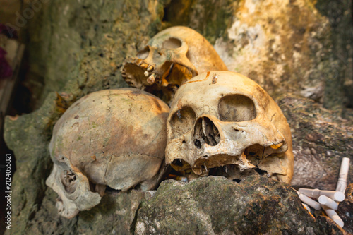 Human skulls with traditional cigarette offerings inside the ancient burial cave of Londa, North Toraja, Indonesia