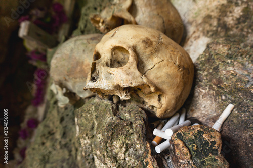 Human skulls with traditional cigarette offerings inside the ancient burial cave of Londa, North Toraja, Indonesia