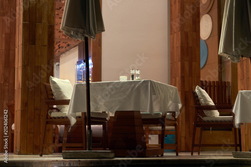 Elegant outdoor dining area at a luxury resort featuring set tables with white tablecloths and chairs under umbrellas at night.