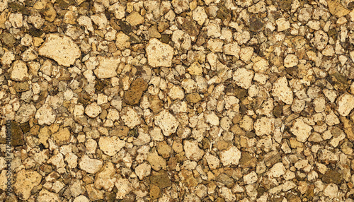 Close up down view of small crushed brown and beige stones forming a rough textured ground surface for natural background use