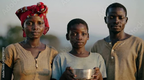 African family holding metal bowl in outdoor setting, medium shot