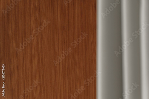 Photography Close interior view contrasting a flat brown wood grain panel against soft grey folded drapes