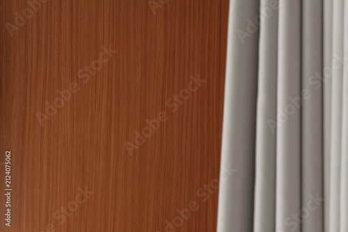 Canvas Print Close interior view contrasting a flat brown wood grain panel against soft grey folded drapes