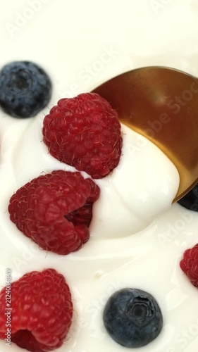  White Yogurt with fresh berries scoop with spoon from a bowl, close up. Healthy breakfast idea