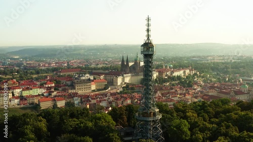 Petrin lookout tower rises above green hill park in Prague. Historic Prague Castle and cityscape create famous tourist attraction. Scenic view represents european travel and destination.