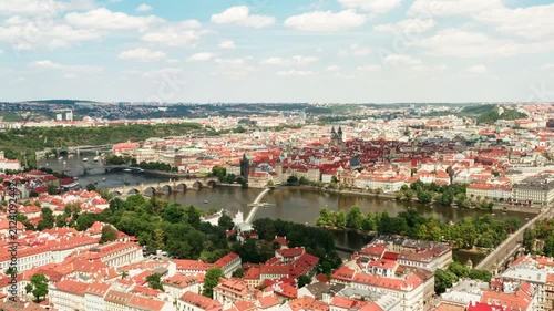 Historic landmark Charles Bridge crosses Vltava river in central Prague. European architecture showcases iconic red roofs. Scenic cityscape represents travel and tourist attraction.