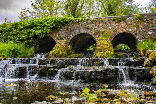Killukin Cascade Waterfall and historic stone bridge in County Roscommon Ireland with cascading water, moss-covered rocks and lush riverside scenery