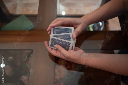 Close up of teenage hands shuffling a deck of playing cards on a glass table before a card game at home