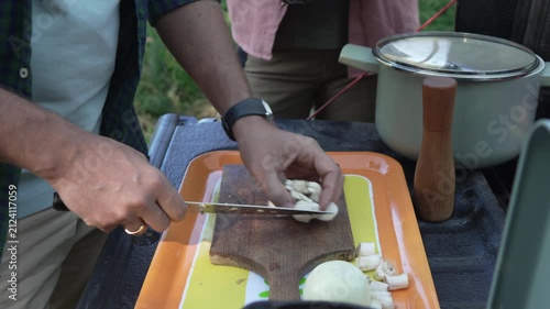 Man slicing mushrooms while camping outdoors