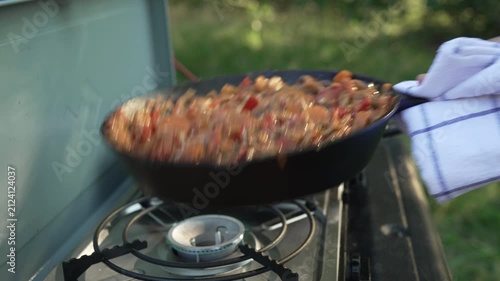 Chef tossing vegetable stew in a pan while camping
