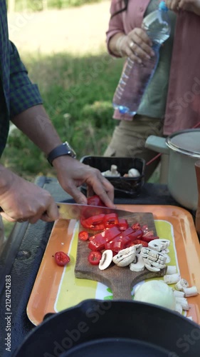 Man slicing fresh red peppers and mushrooms for camping meal