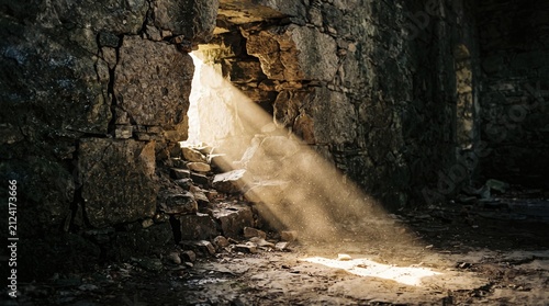 Sunbeam entering an ancient stone ruin illuminating dust particles creating a mystical atmosphere for historical or fantasy concepts
