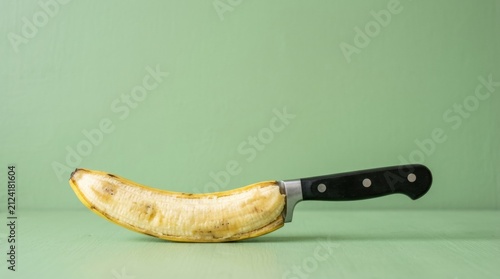 Surreal kitchen knife with a soft banana blade depicting uselessness on a green background with ample copy space for food processing campaigns