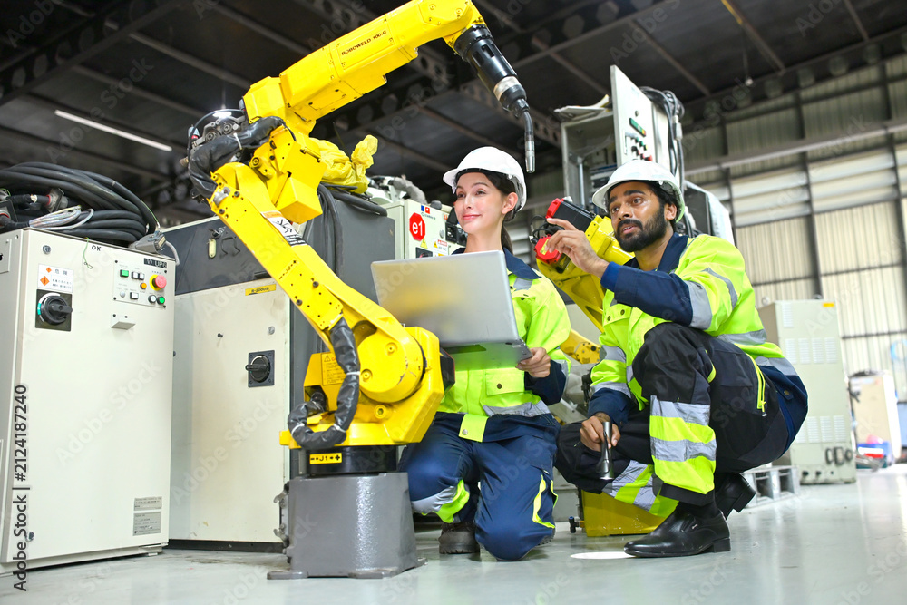 Fototapeta premium Workers use a robot arm to automate tasks in a factory environment during the day