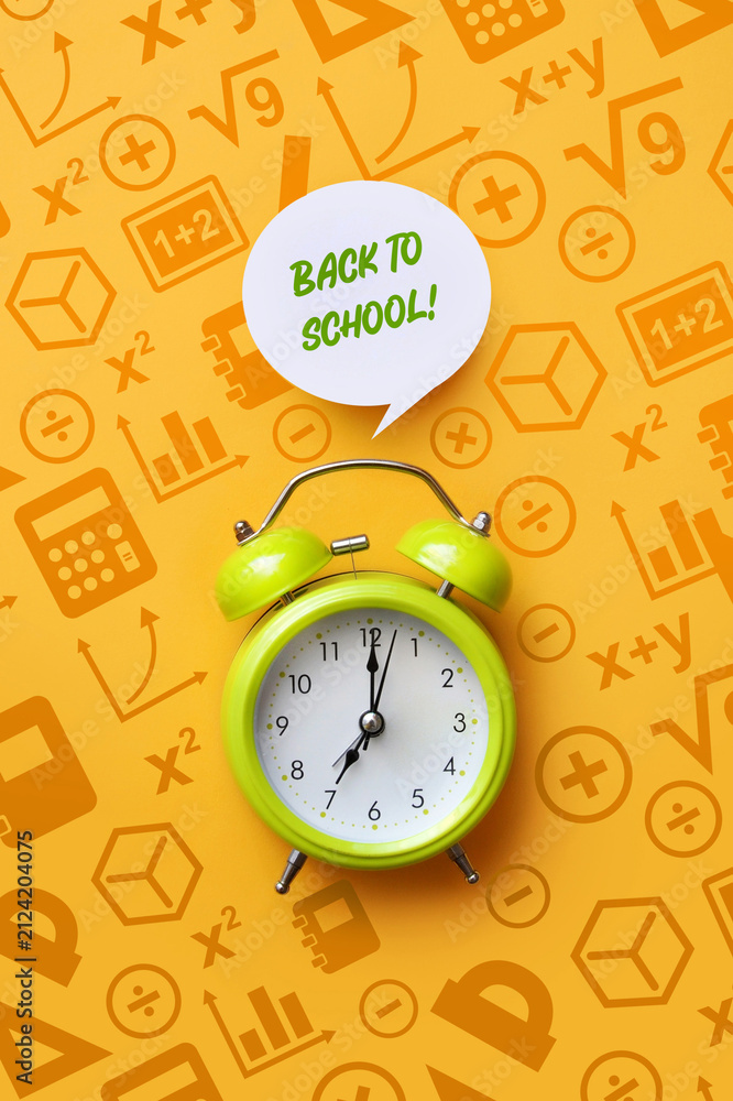 Fototapeta premium Green alarm clock on educational background with back to school message