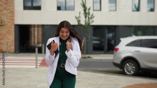 Excited young business woman celebrating success and gesturing yes outdoors, slow motion