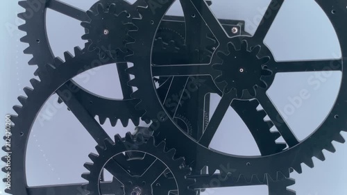 Three interlocking metal gears rotating at different speeds, transmitting mechanical motion through meshing teeth. Closeup view of movement, principles of power transmission in clean mechanical system