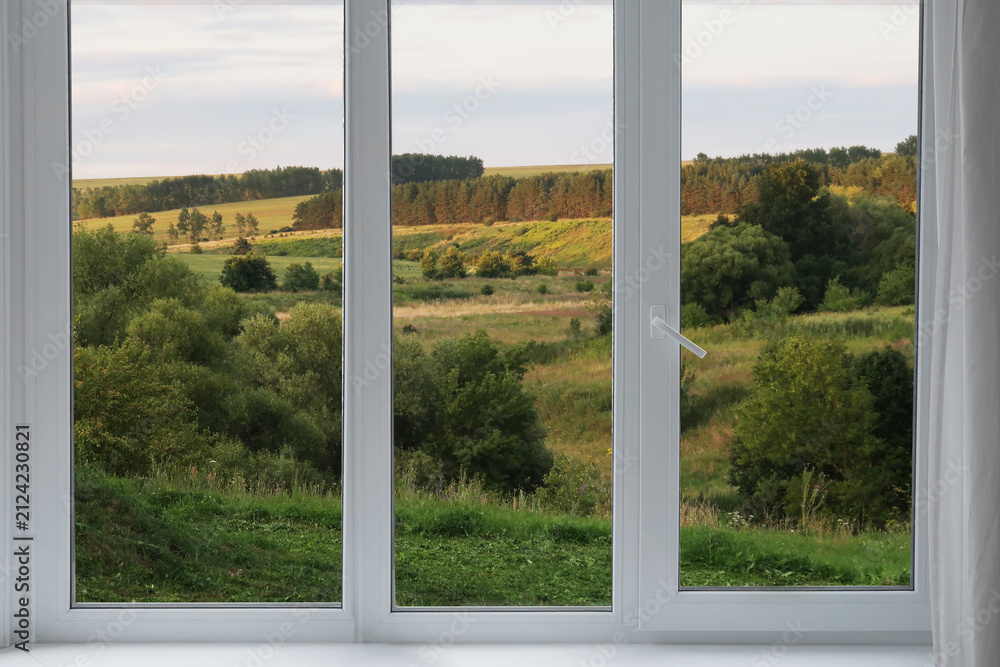 Fototapeta premium A view from the window of a landscape with green slopes and stretches of forest.