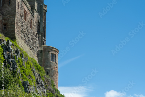 Medieval clifftop castle against a clear blue sky, dramatic coastal fortress rising above rugged landscape with open space and copy space for text.
