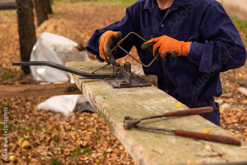Canvas Print Construction worker using manual rebar bender to shape steel stirrups for concre