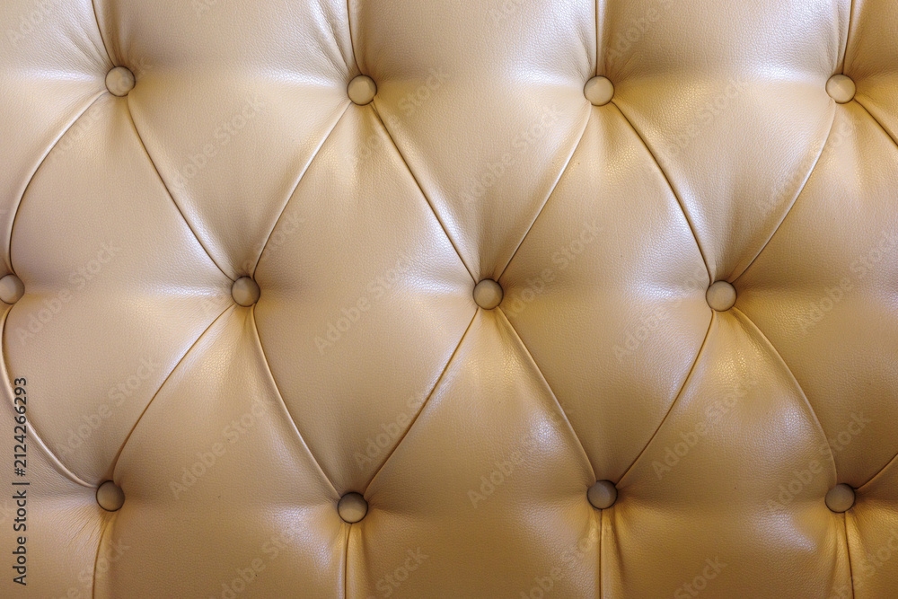 Obraz premium Beige tufted leather upholstery background with buttoned luxury furniture texture.