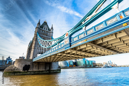 View of the iconic Tower Bridge with its blue steel structure and stone towers over the River Thames in London, England, United Kingdom.