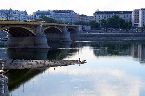 low water level on the Danube river at the Margaret Bridge in Budapest, Hungary. hot temperature, drought. exposed rocky island at the base of the bridge pillar. reflecting water. environment concept