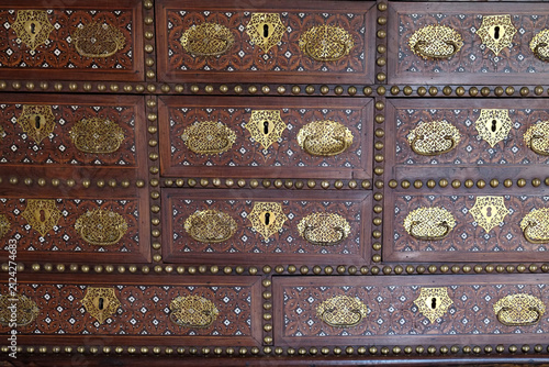 Antique wooden cabinet with ornate brass hardware pattern