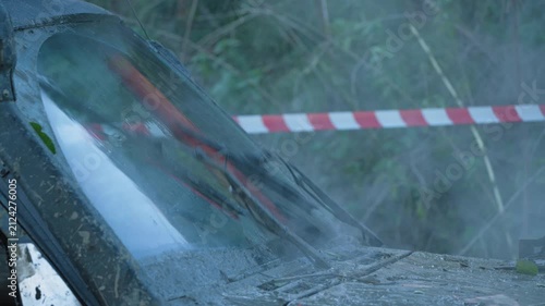 Close-up of dirty off-road car. Wipers clearing mud from windscreen during extreme outdoor rally. Red and white tape in background. Adventurous and rugged scene