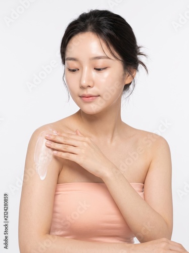 Woman Applying Moisturizing Cream on Shoulder with Calm Expression
