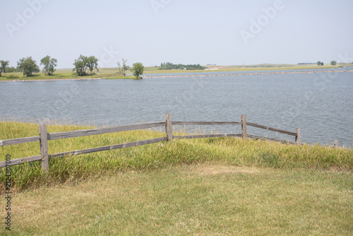 Rustic Wooden Fence Along Peaceful Lake Shore in Rural Setting