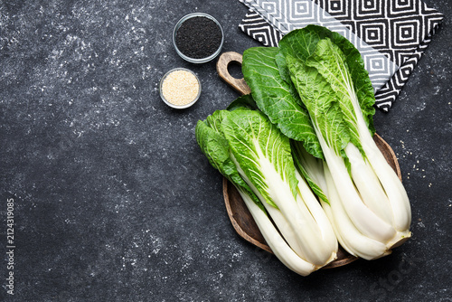 Quadro su tela Fresh bok choy cabbages, black and white sesame seeds on gray textured table, flat lay